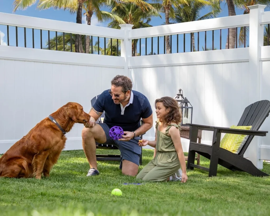 dog and family playing in yard with a foremost fence
